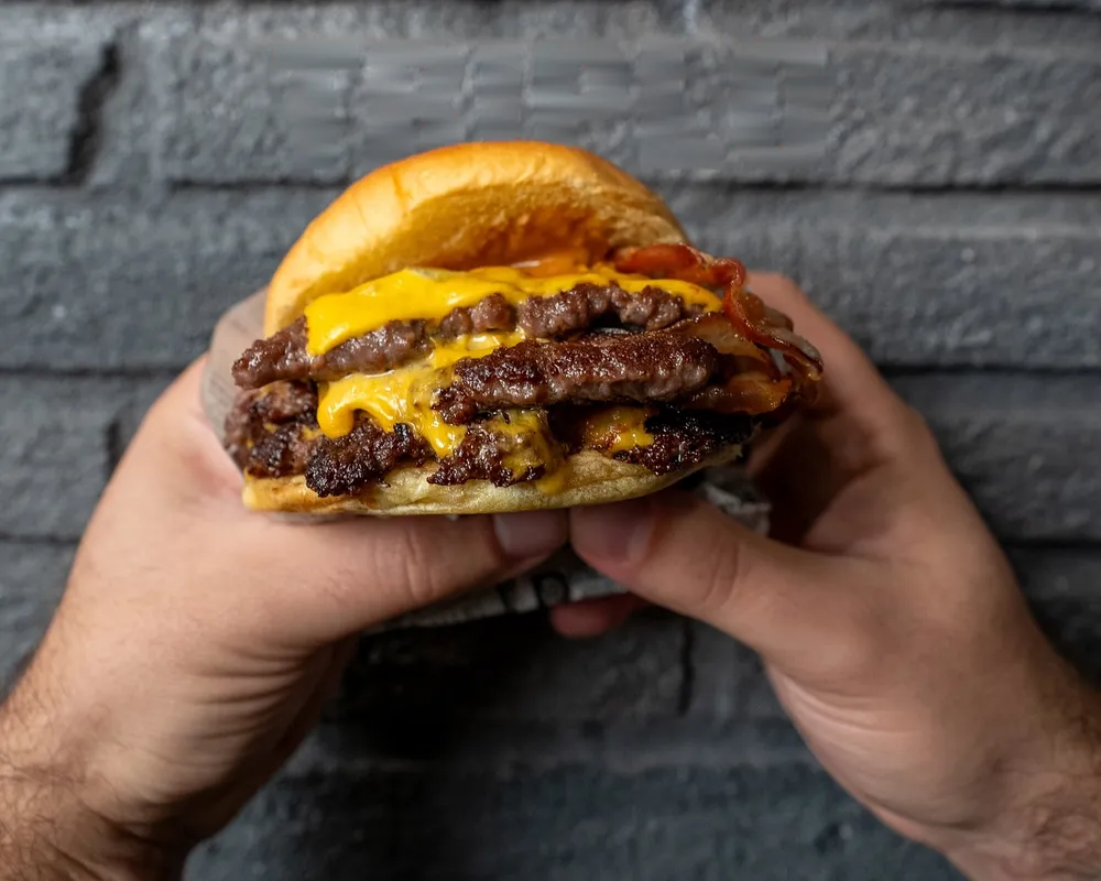 Il Mr Durden tenuto con due mani: smash con cheddar fuso e bacon croccante