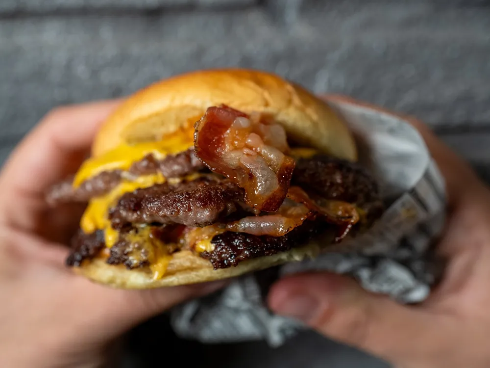 Un Mr Durden tenuto con due mani: tre smash, cheddar fuso e bacon croccante